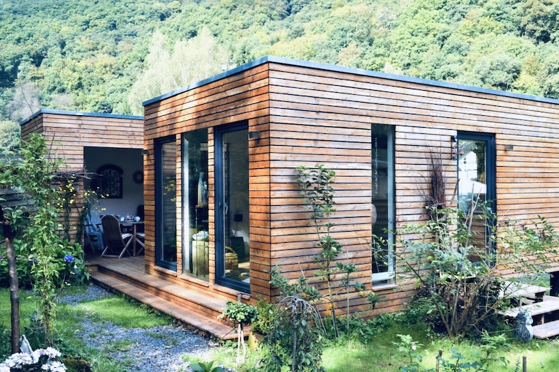 Das Bild zeigt ein Tiny House, das dauerhaft bewohnt wird mit Wald im Hintergrund und wofür eine Baugenehmigung benötigt wird